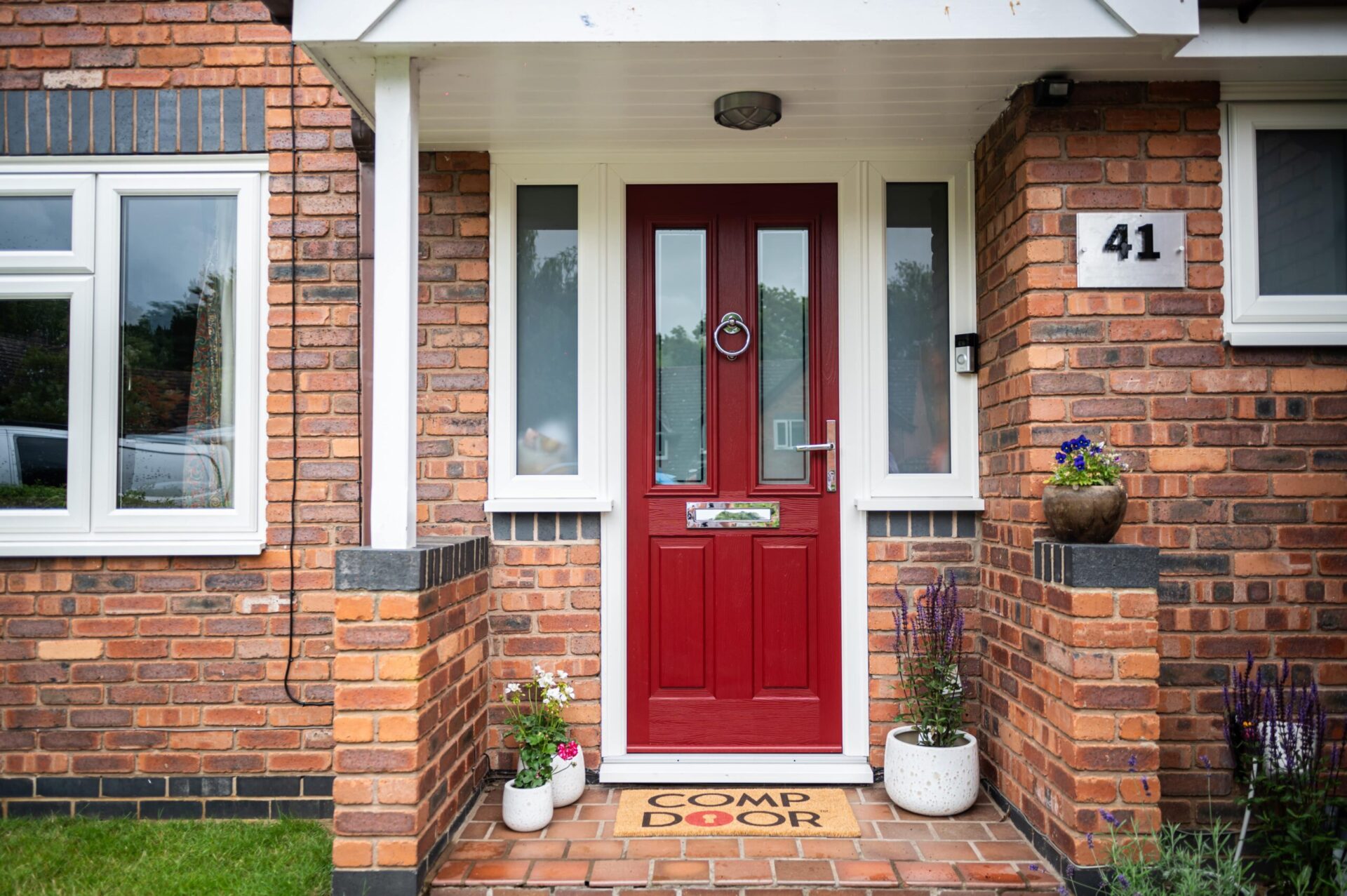 Deep red Comp Door front door with traditional panels, glazed sidelights and a ring knocker