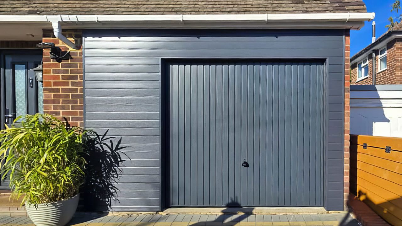 White Garador up-and-over garage door fitted between brickwork on a detached garage